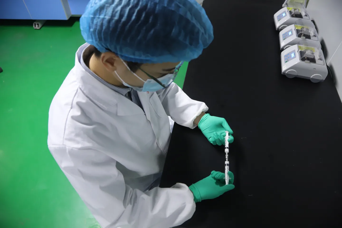 Laboratory operator using a two-syringe mixing technique at the preparation bench